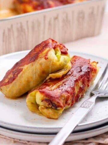 Two cabbage rolls on a plate with fork.
