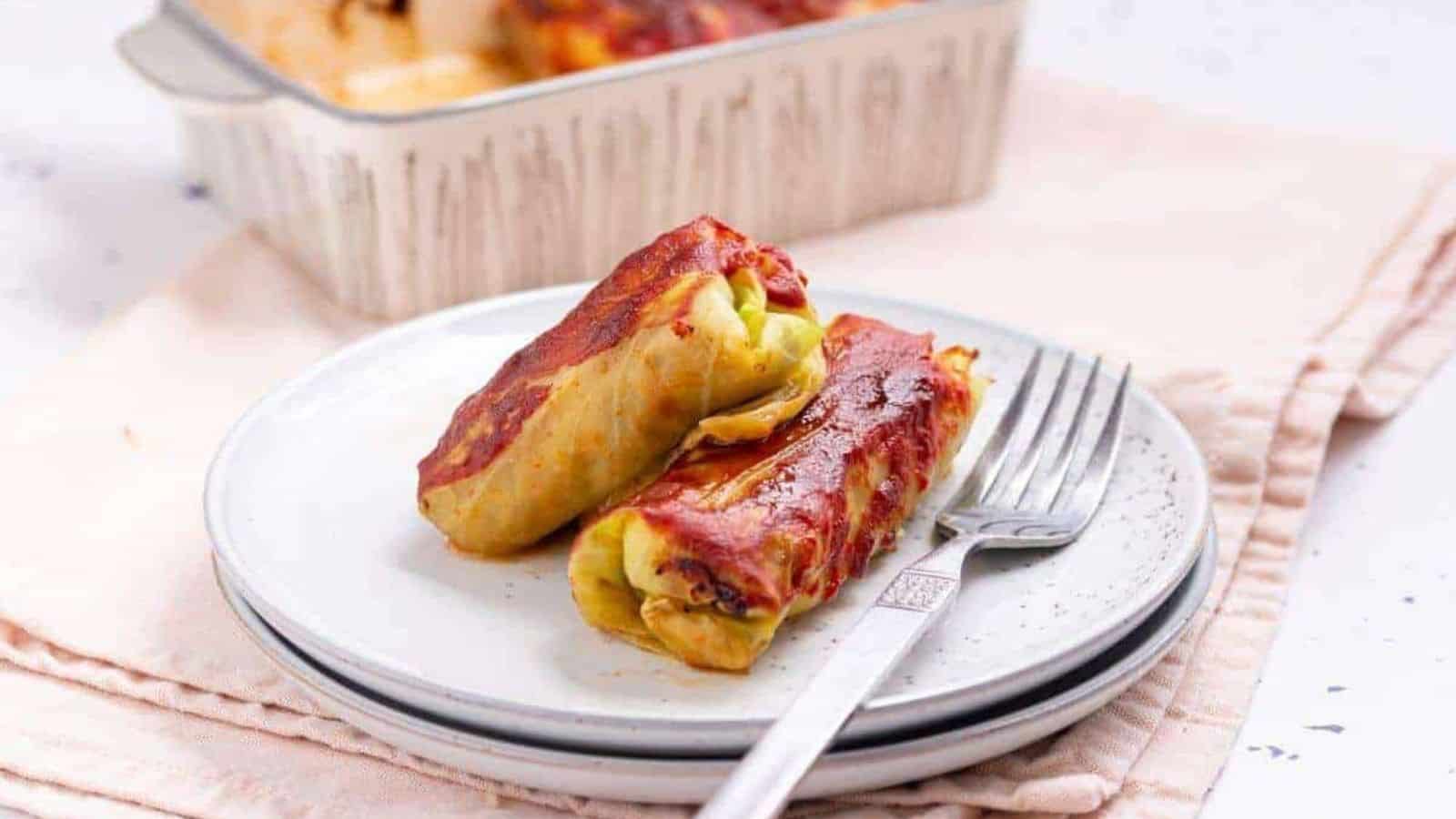 Two cabbage rolls on a plate with fork.