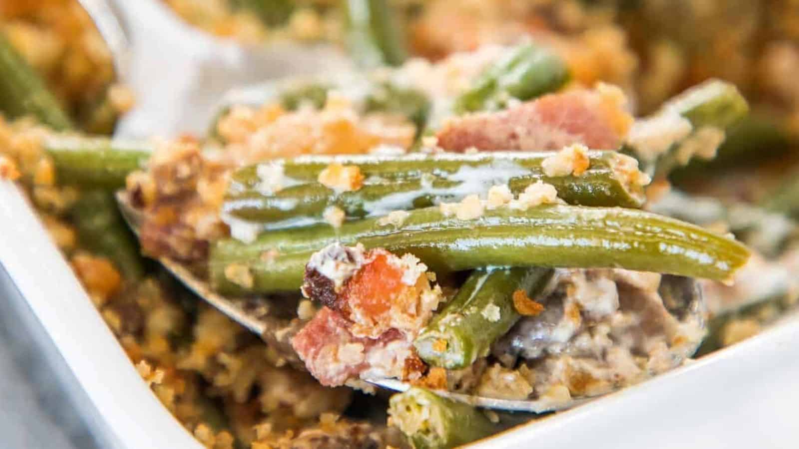 Green bean casserole with bacon being served with a spoon.