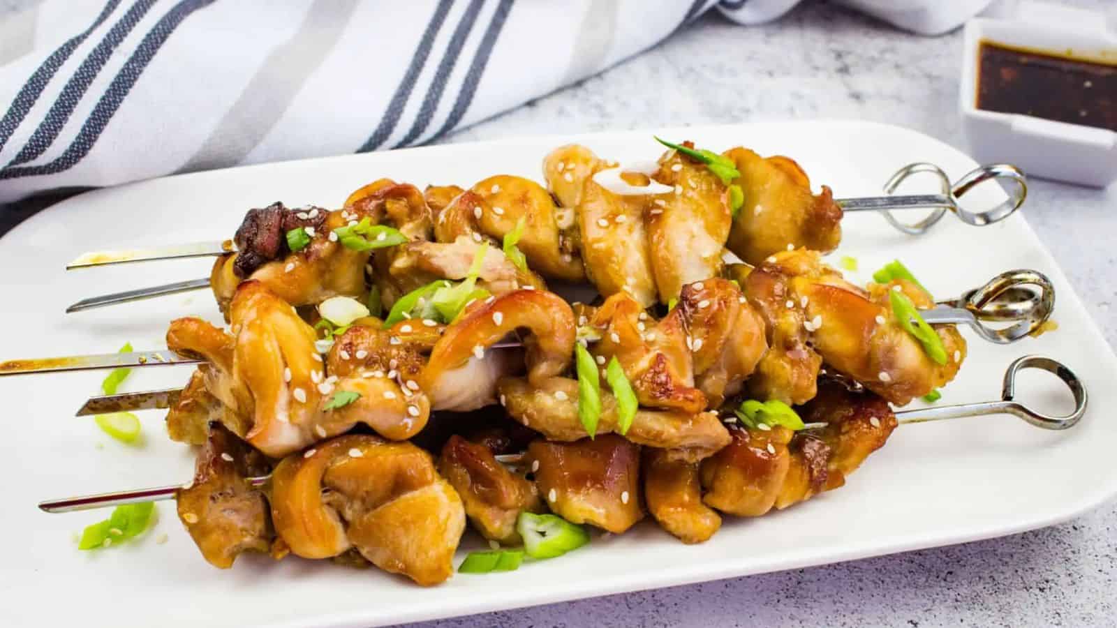 Keto teriyaki chicken skewers on a white plate.