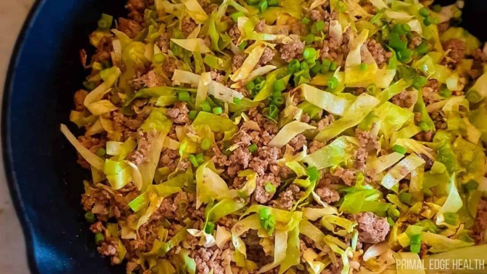 A picture of cabbage stir fry in cast iron skillet.