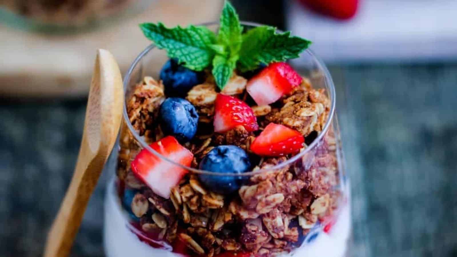 A parfait in a glass layered with yogurt and gluten free granola.