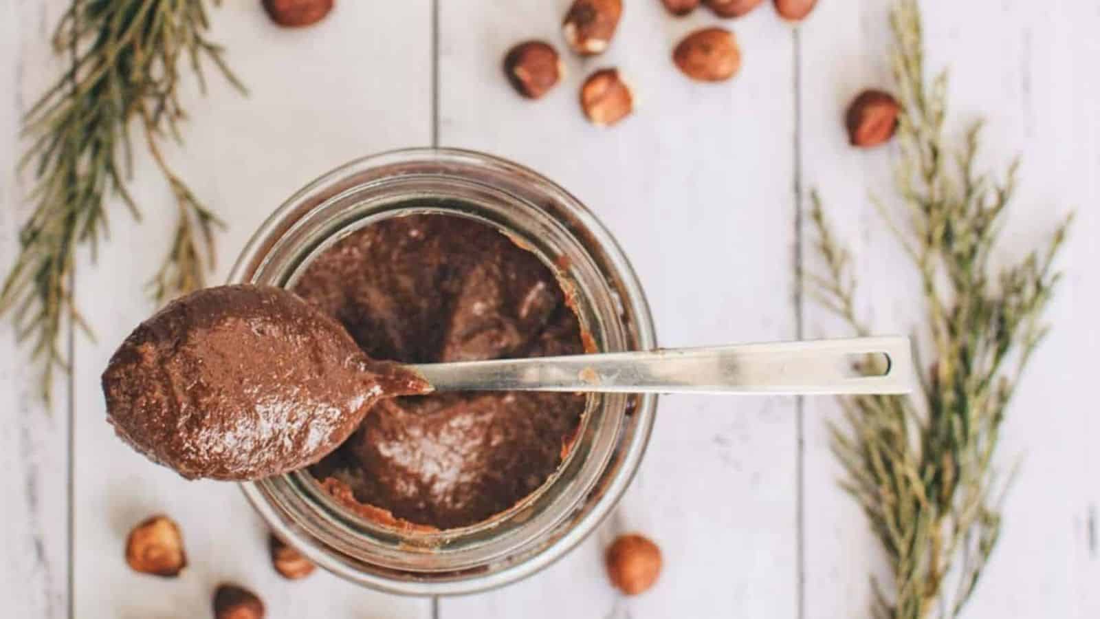Homemade vegan nutella spread in a glass with a spoon on top.