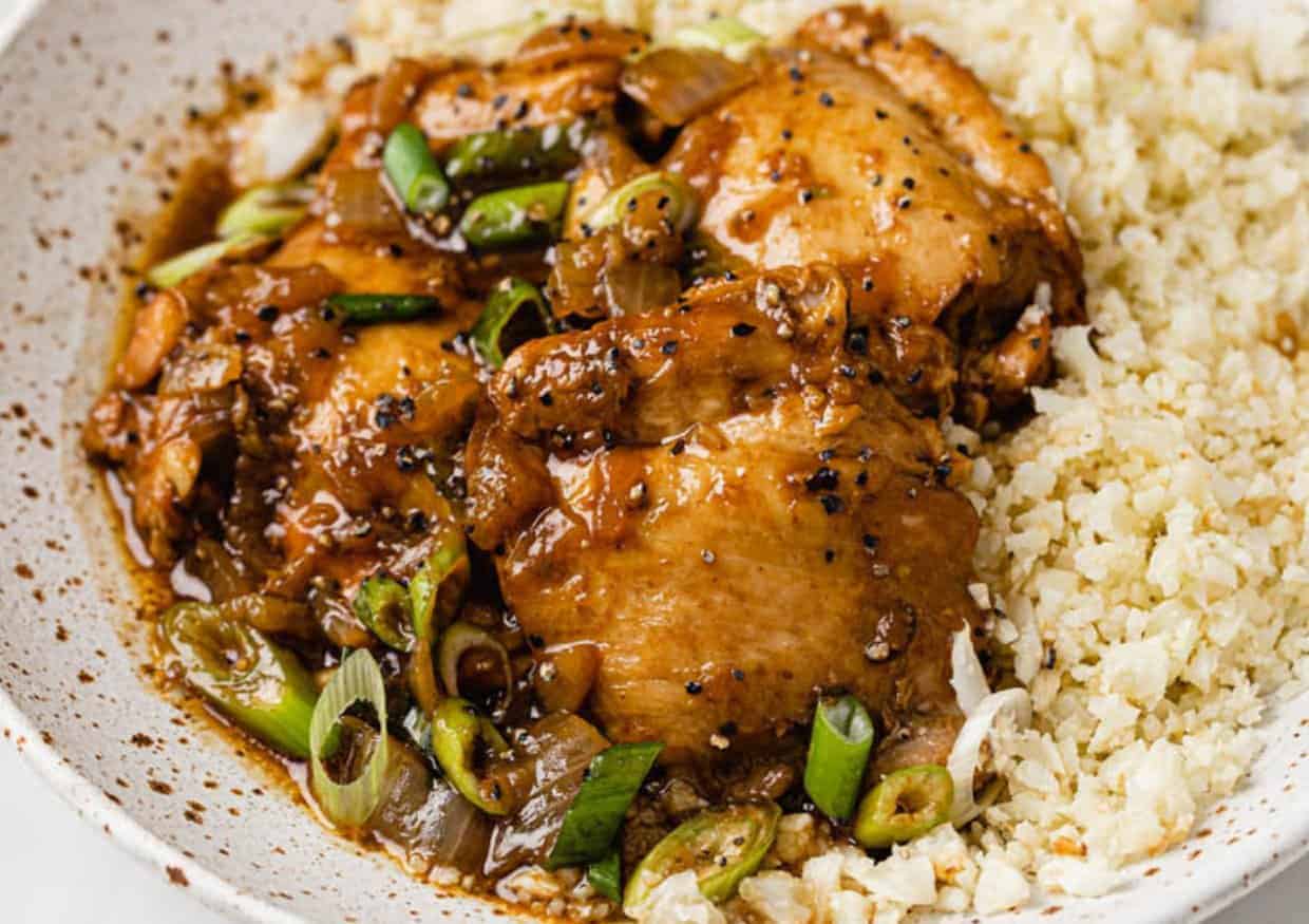 Instant pot chicken adobo in a bowl atop cauliflower rice.