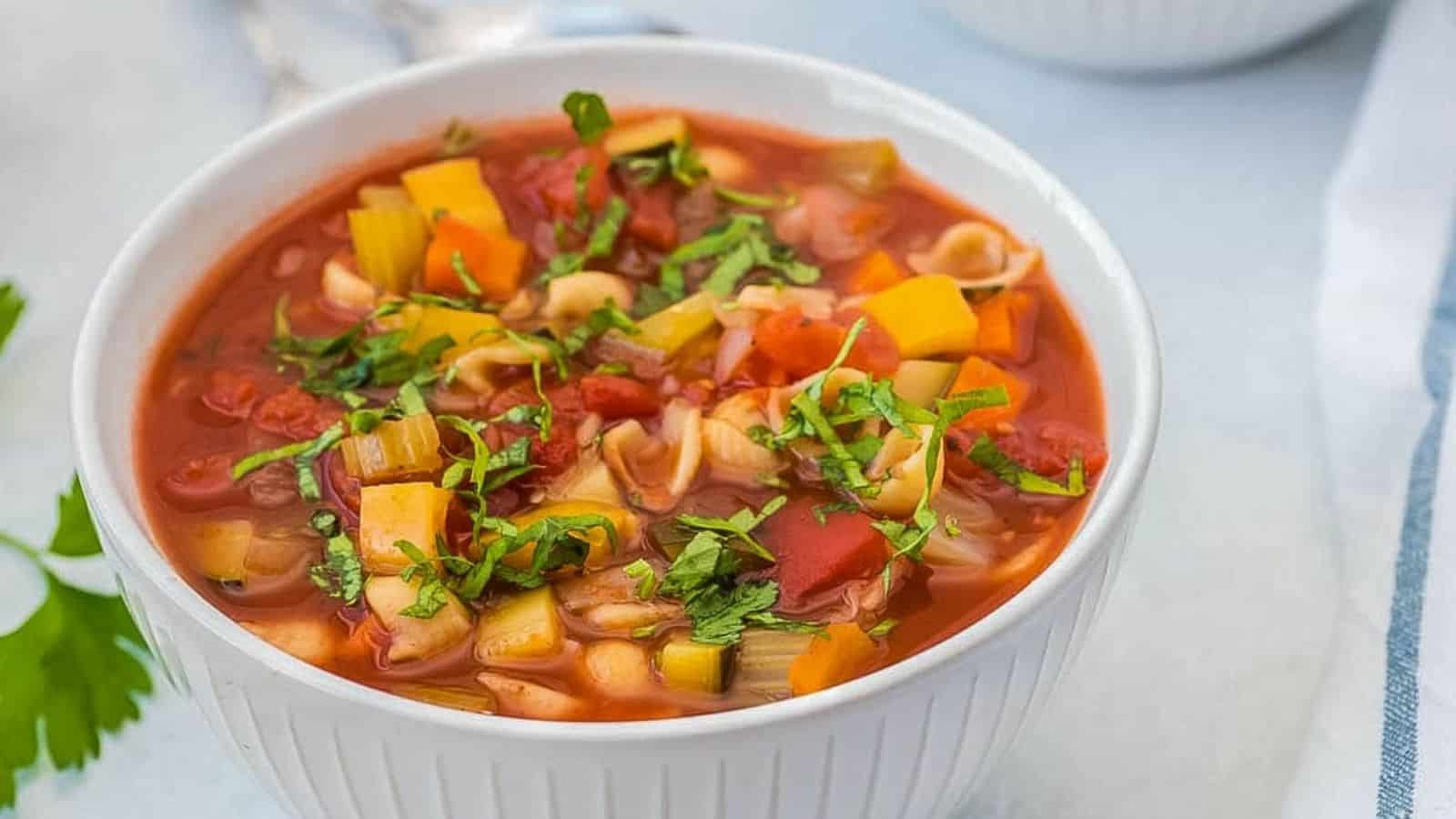 Olive Garden Minestrone Soup in a white bowl topped with basil.