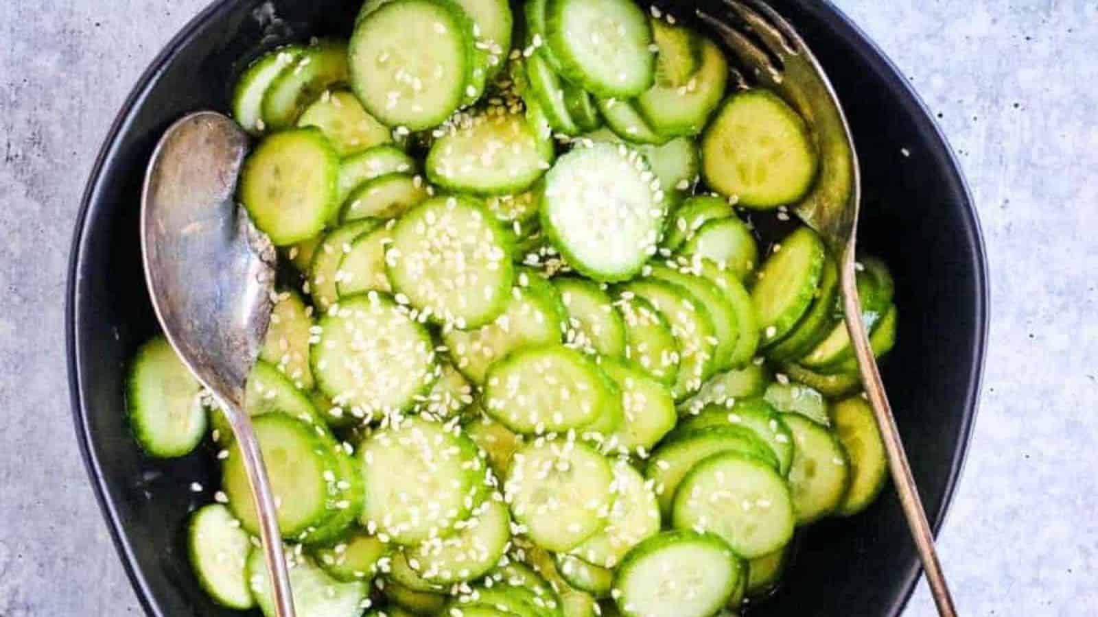 A black bowl of Japanese cucumber salad garnished with sesame seeds.