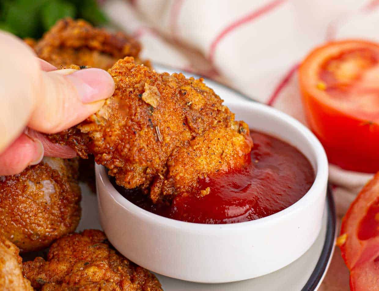 A hand holding a piece of fried chicken.