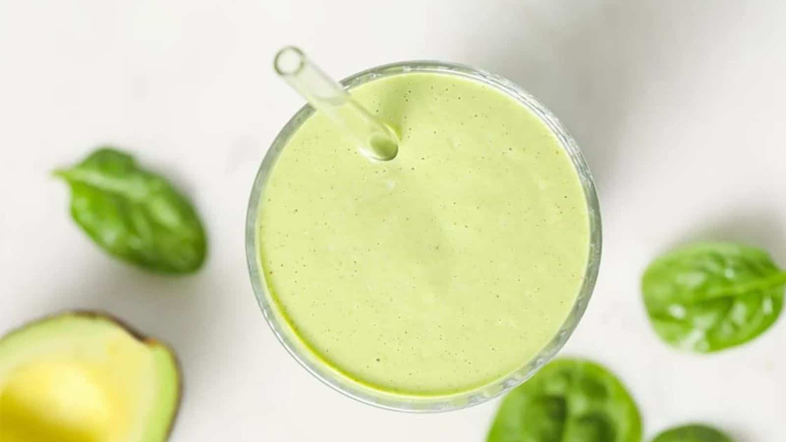 A spoon of keto green smoothie atop a blender.