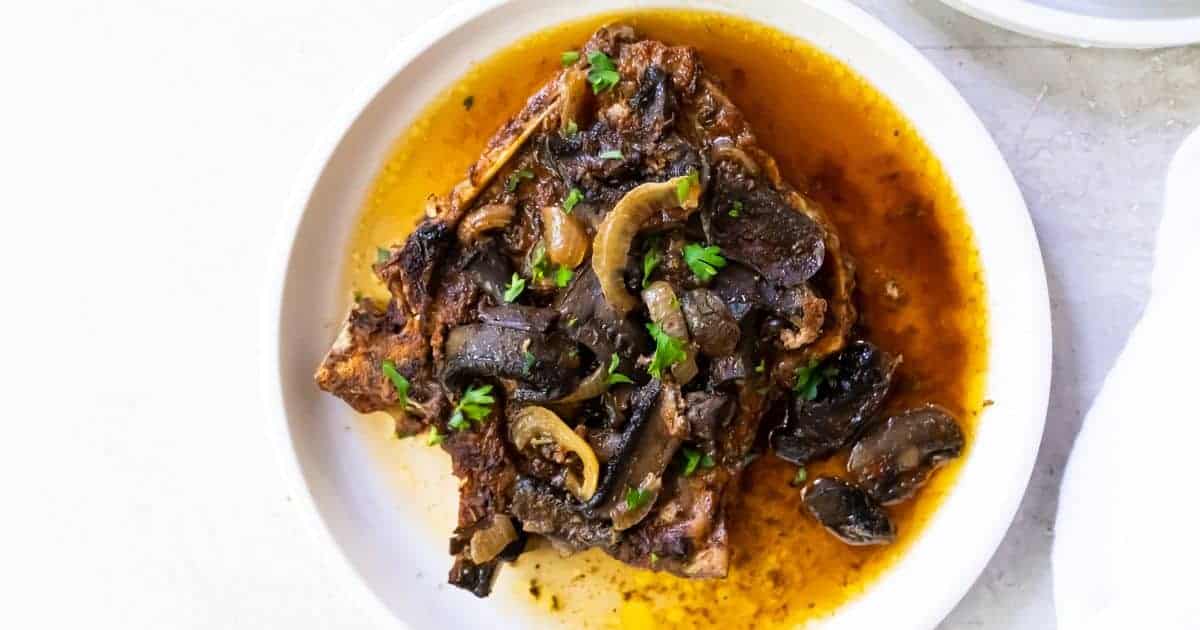 Crock Pot Smothered Pork Chops covered in gravy with parsley on top.