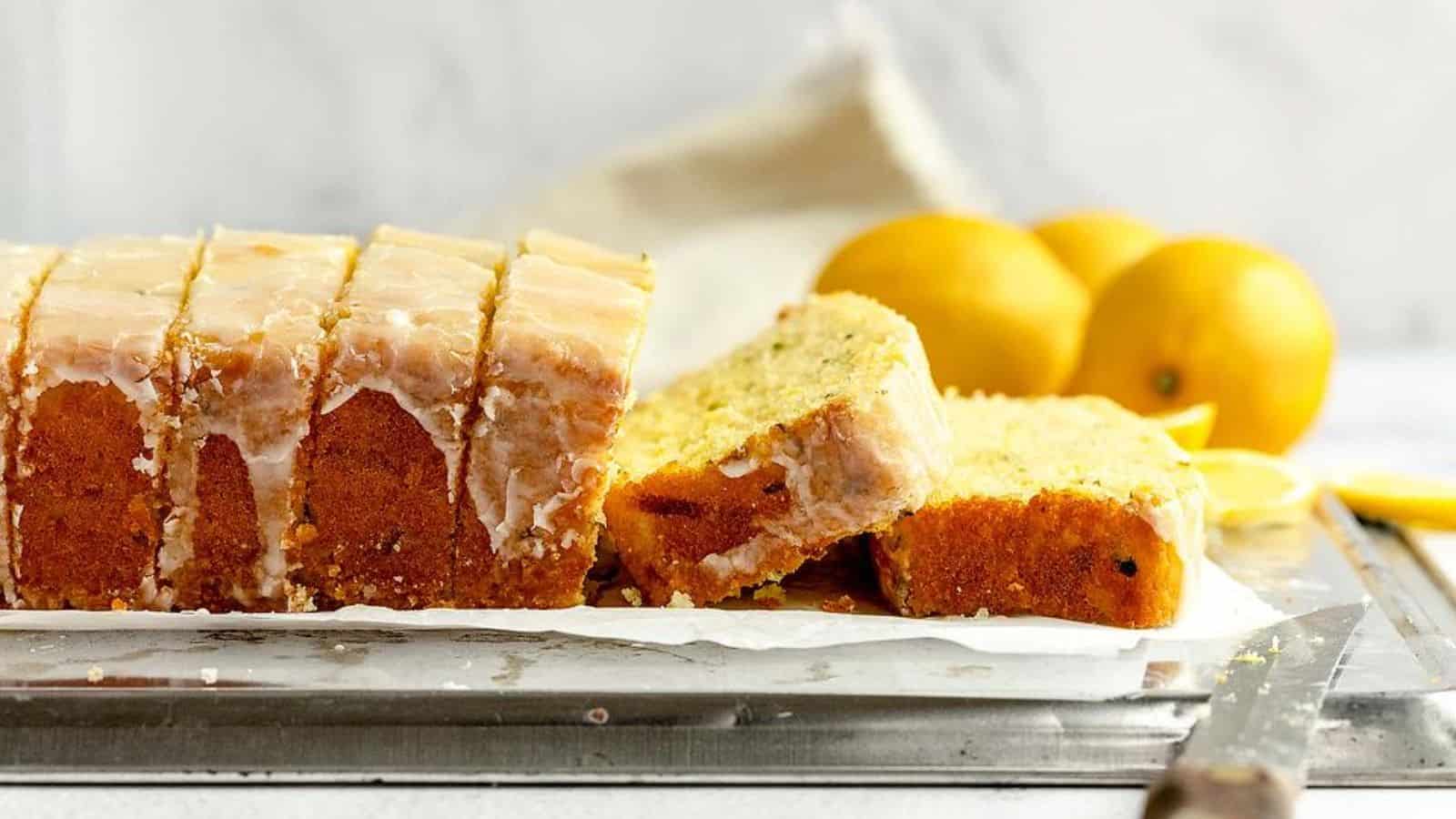 Sliced loaf of lemon zucchini bread with fresh lemons on the background.