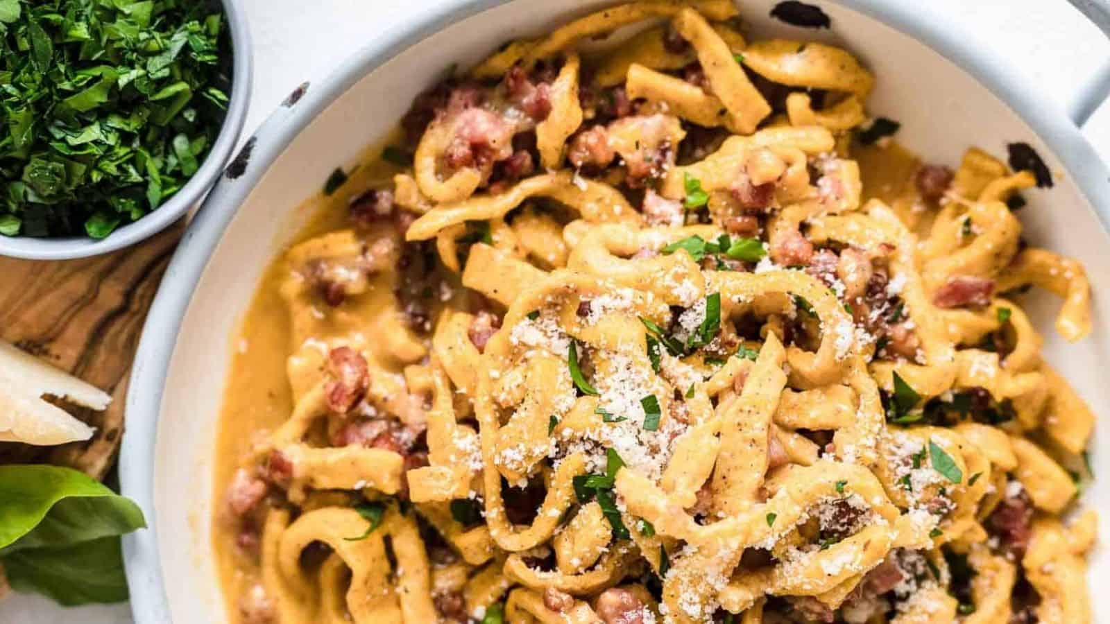 Pasta Carbonara inside a bowl with herbs and bacon.