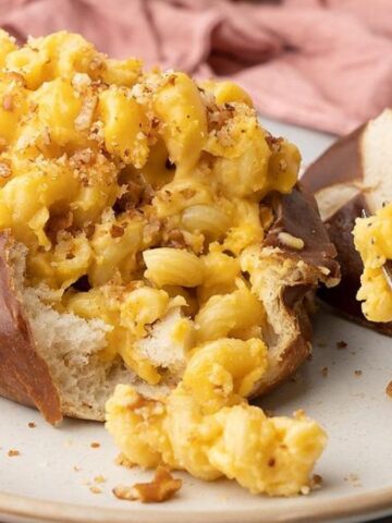 Mac beer chese in a mini pretzel bowl with a fork in a plate.