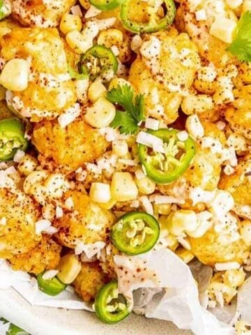Mexican street corn over tater tots in a white bowl.