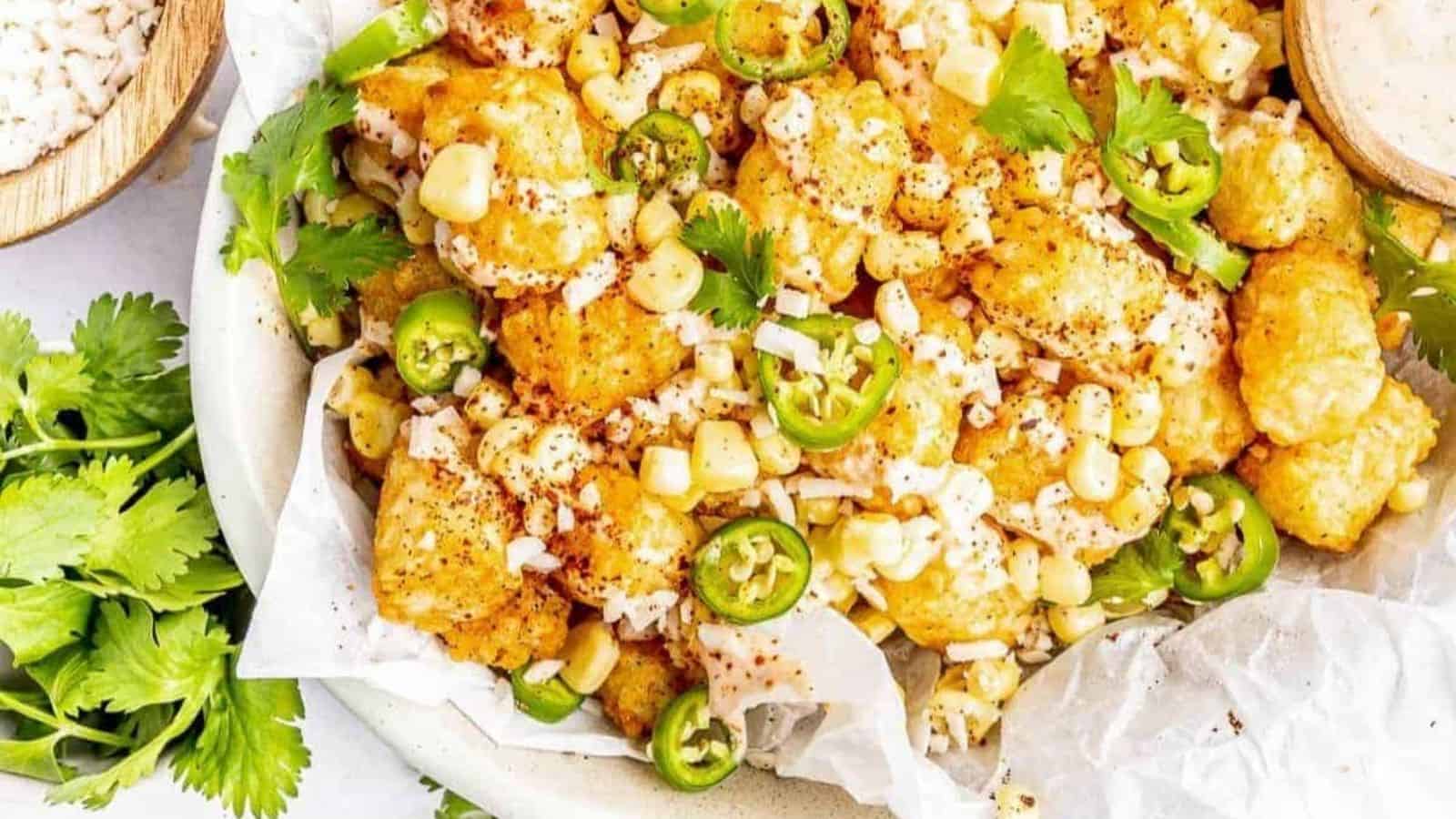 Mexican street corn over tater tots in a white bowl.