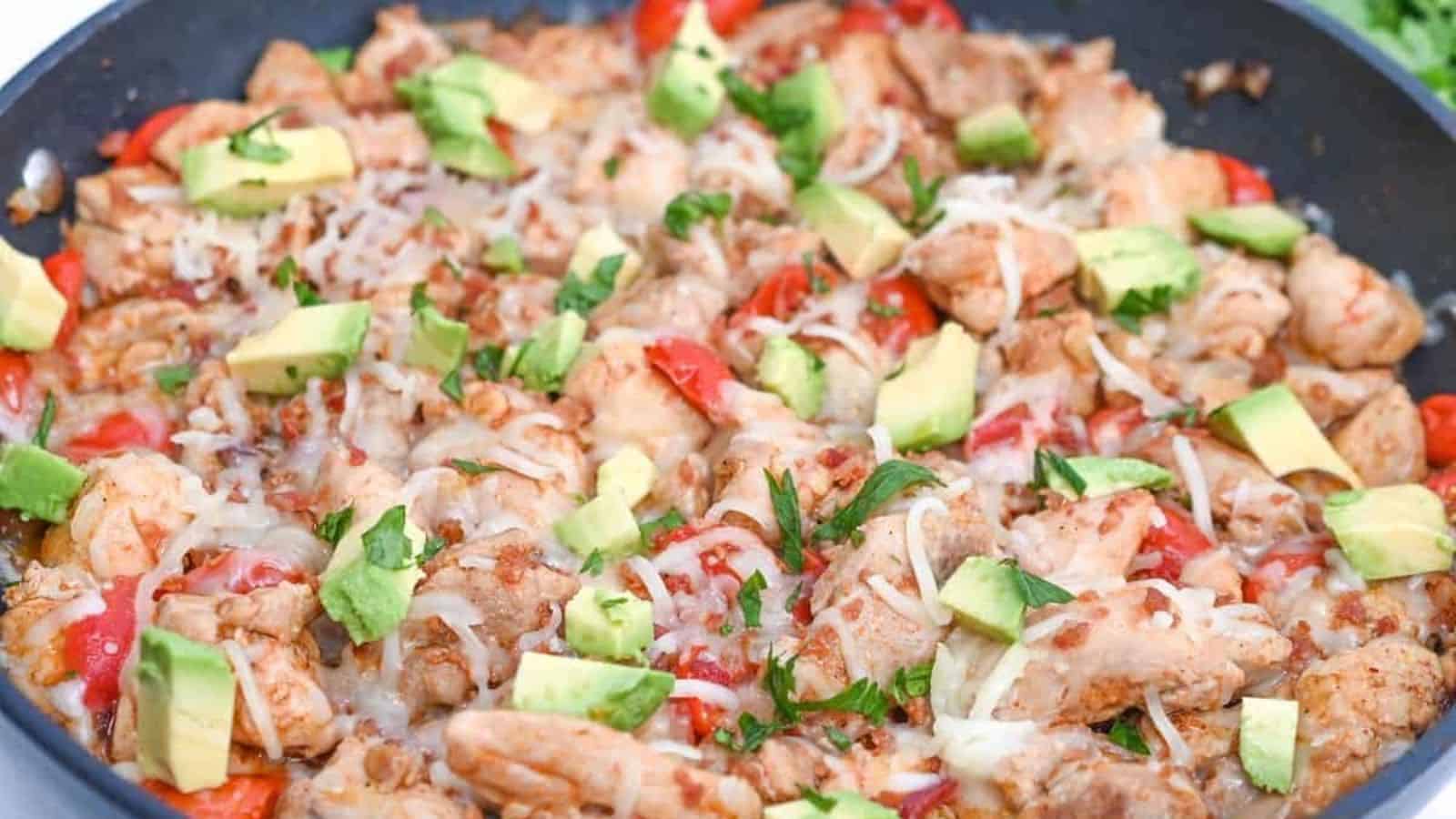 Chicken fajitas in a skillet with avocado.