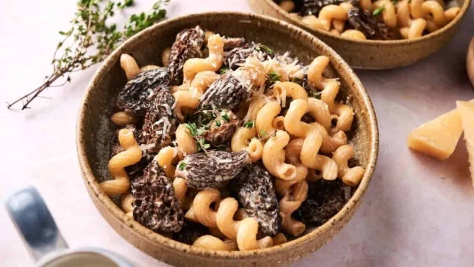 Close-up image of morel mushroom pasta in a brown bowl.