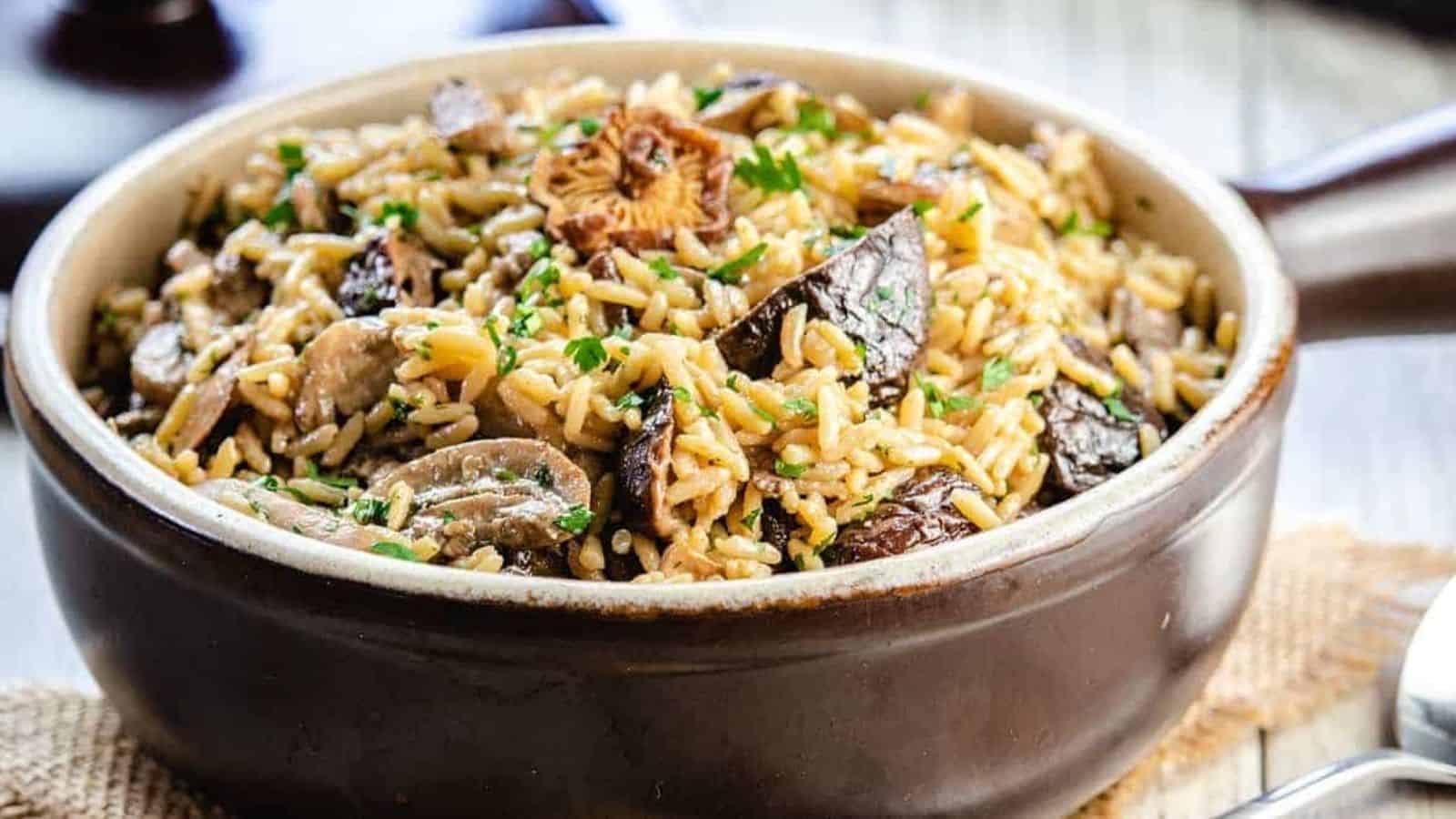 Mushroom rice pilaf in a serving dish with the lid behind it.