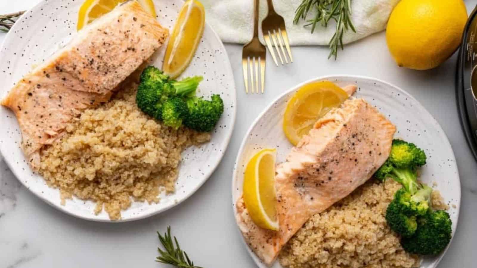 Top view of 2 plates with ninja food salmon with lemon slices, broccoli, and rice.