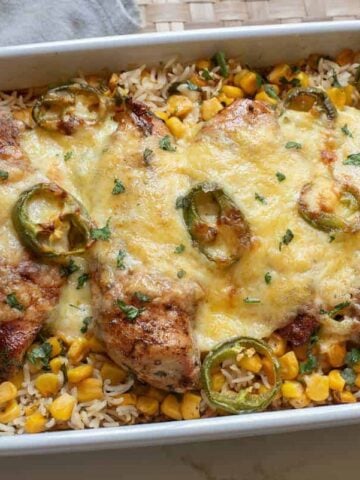 Chicken and rice with jalapenos and cheese in a white baking dish.