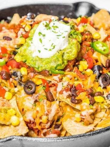 Hot nachos fresh from the oven topped with guacamole and sour cream.