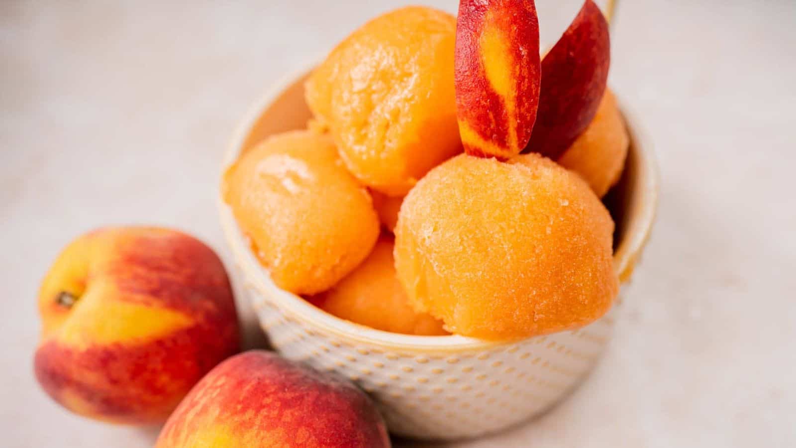 A bowl of perfect peach sorbet with fresh peaches.