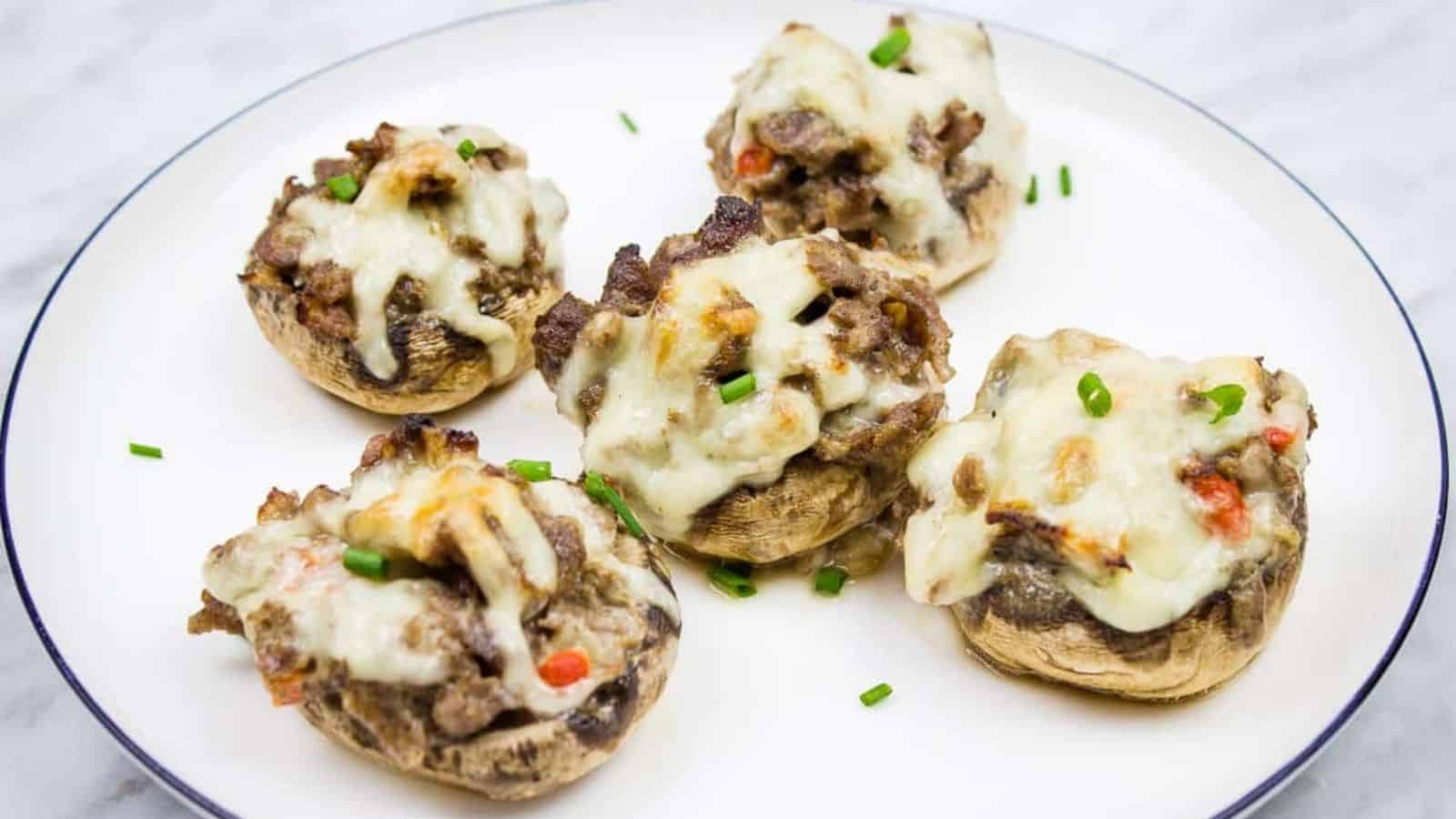 Five stuffed mushrooms on a white plate.