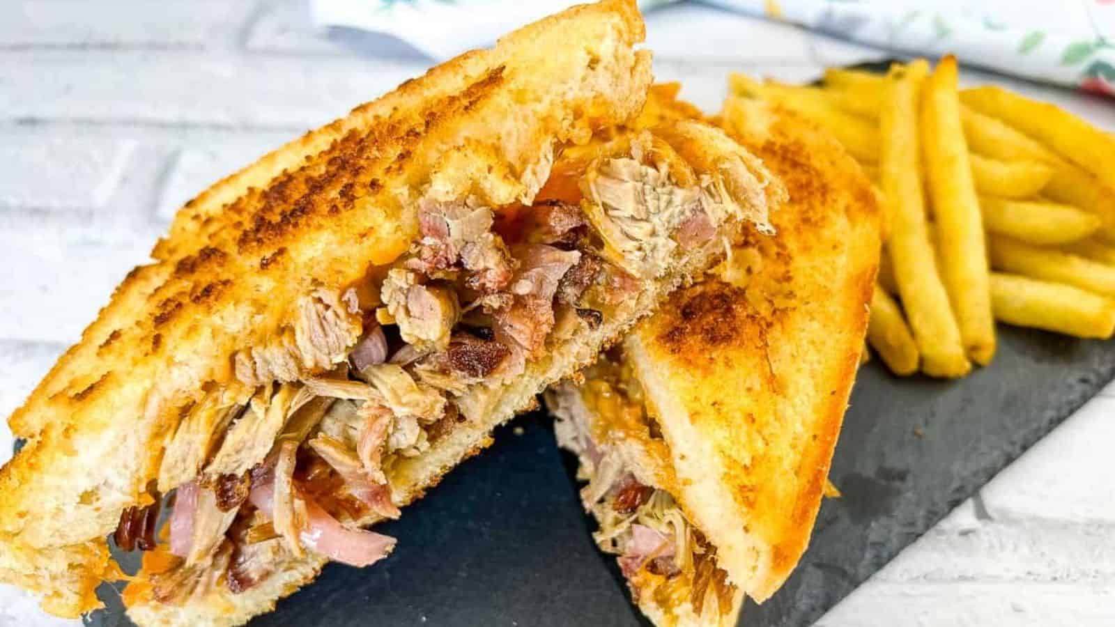 A pulled pork grilled cheese sandwich on a slate plate.