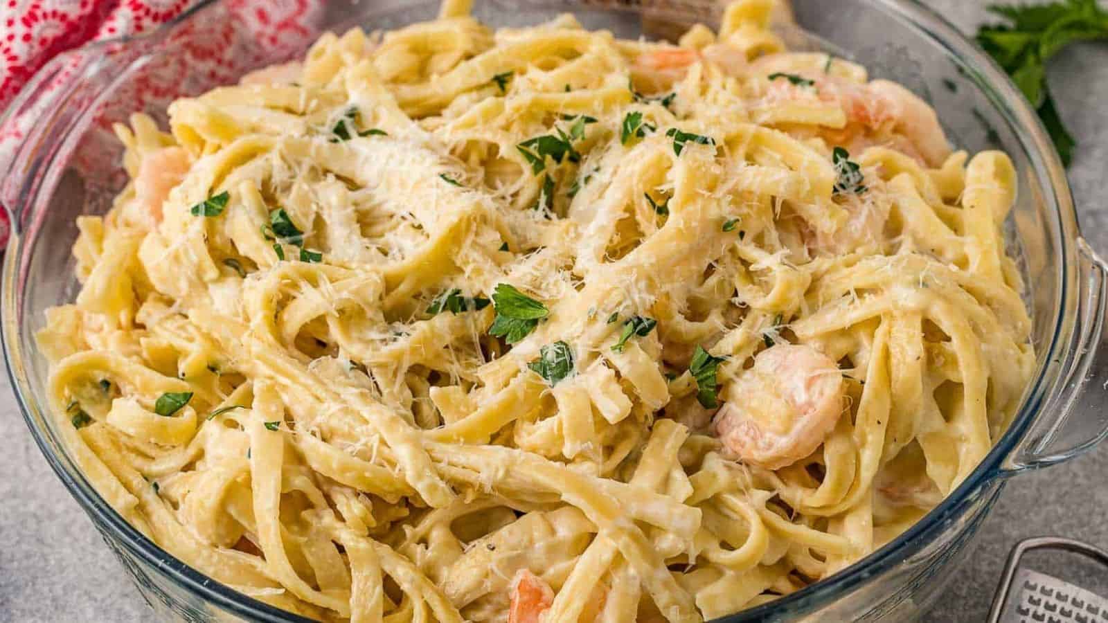 Shrimp and fettuccine pasta in a large glass bowl.