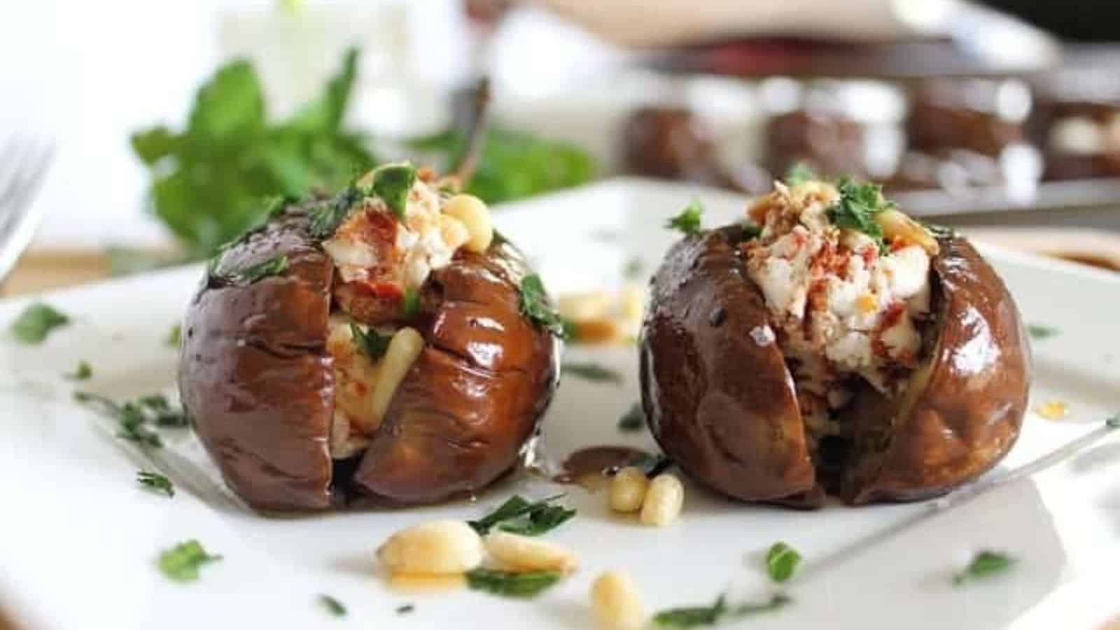 Two roasted baby eggplants with goat cheese stuffing on a plate.