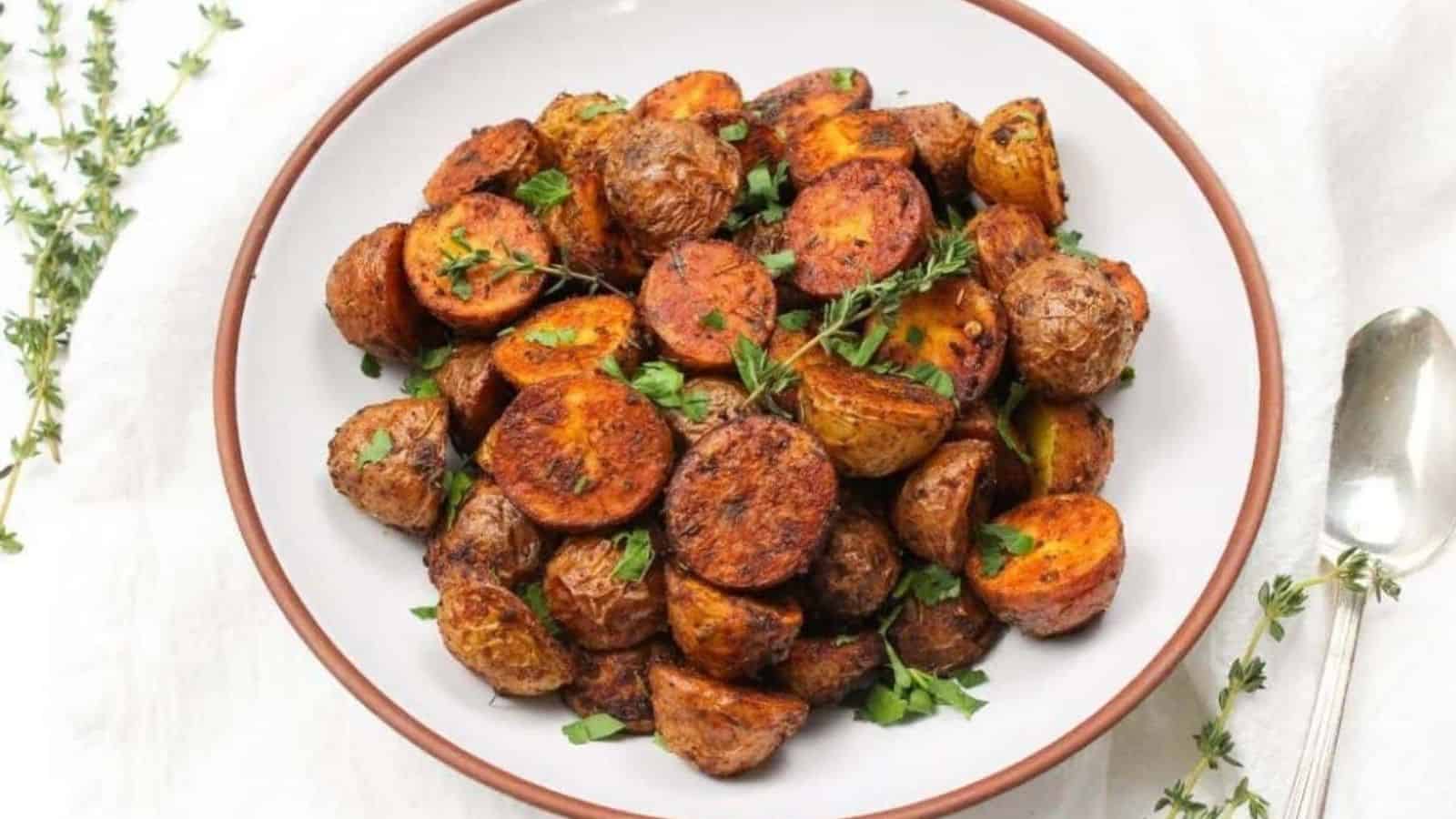 A white bowl with crispy roasted halved mini potatoes seasoned with garlic powder and paprika.