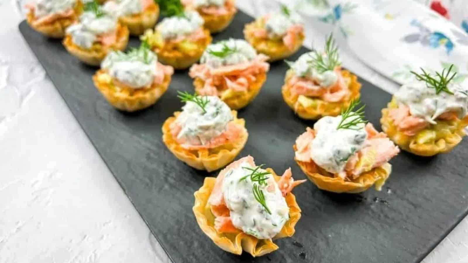 Salmon and leek phyllo tartlets in a black plate.