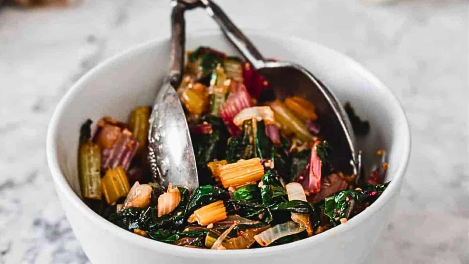 Side view of white bean salad in bowl with tongs.