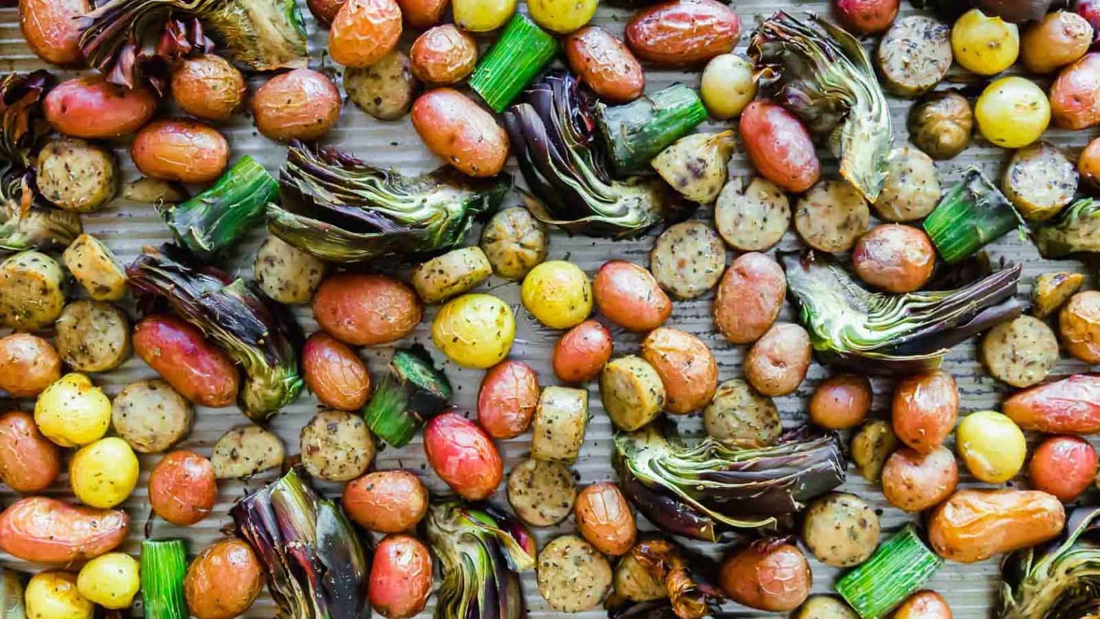 An image of a sheet pan sausage and veggies with purple artichokes.