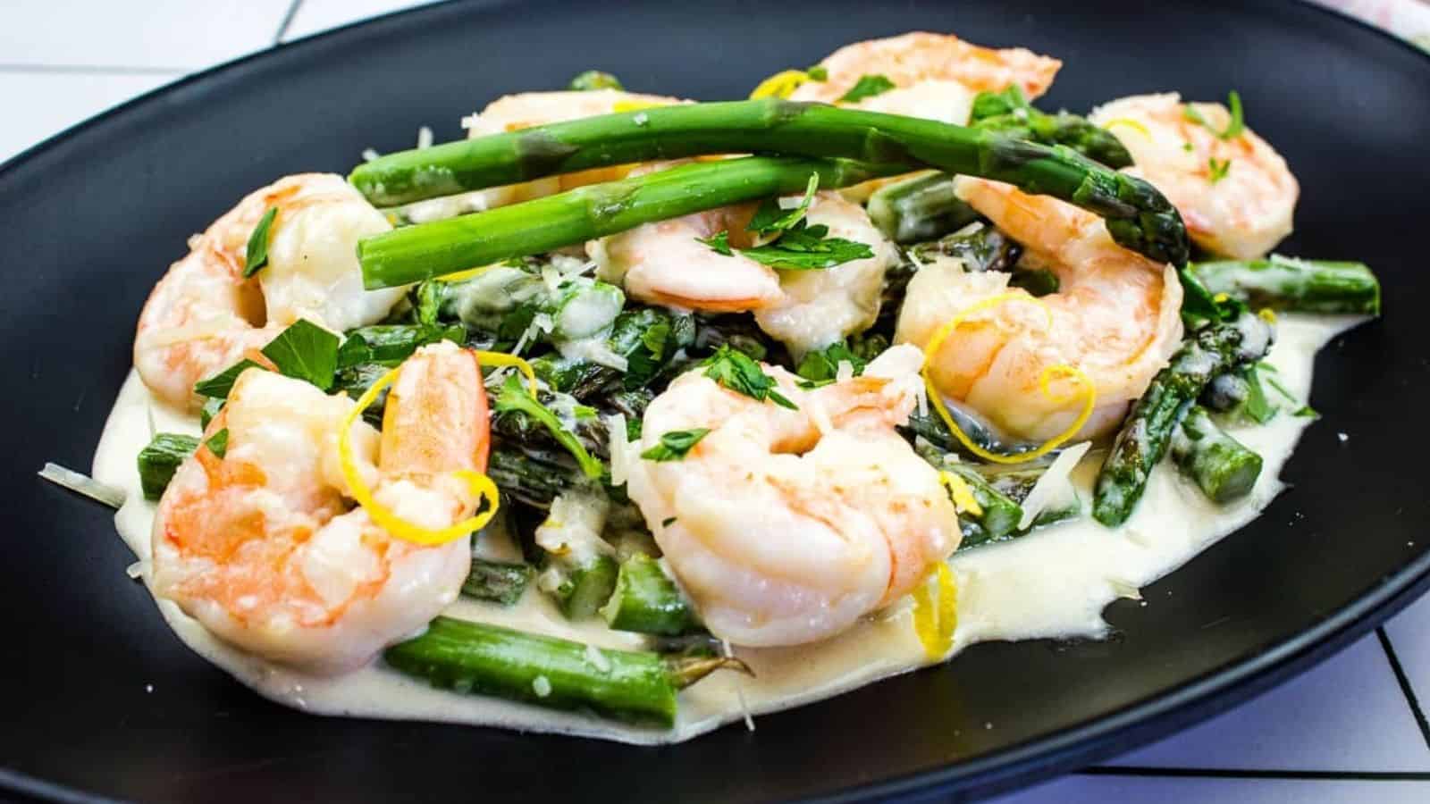 Shrimp & Asparagus Alfredo on a black plate.