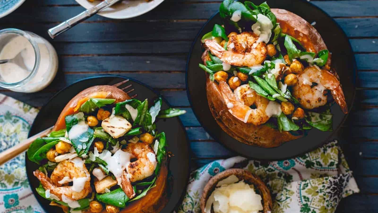 Overhead image of two plates of shrimp caesar salad stuffed sweet potatoes.