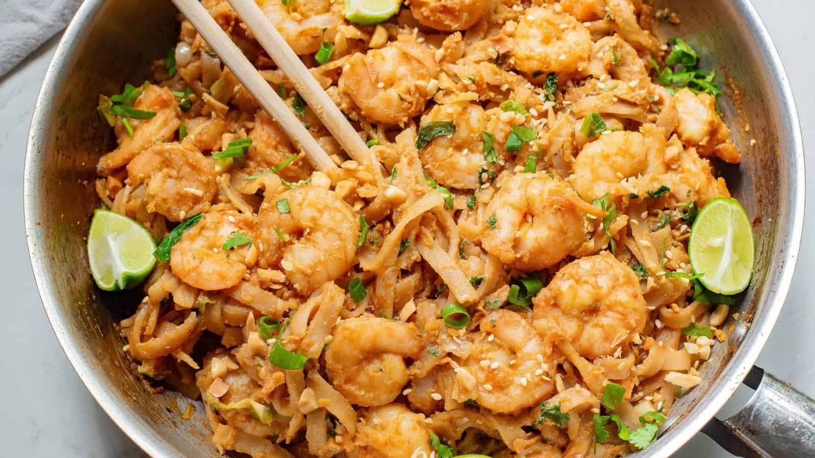 A pan full of shrimp and noodles with chopsticks.