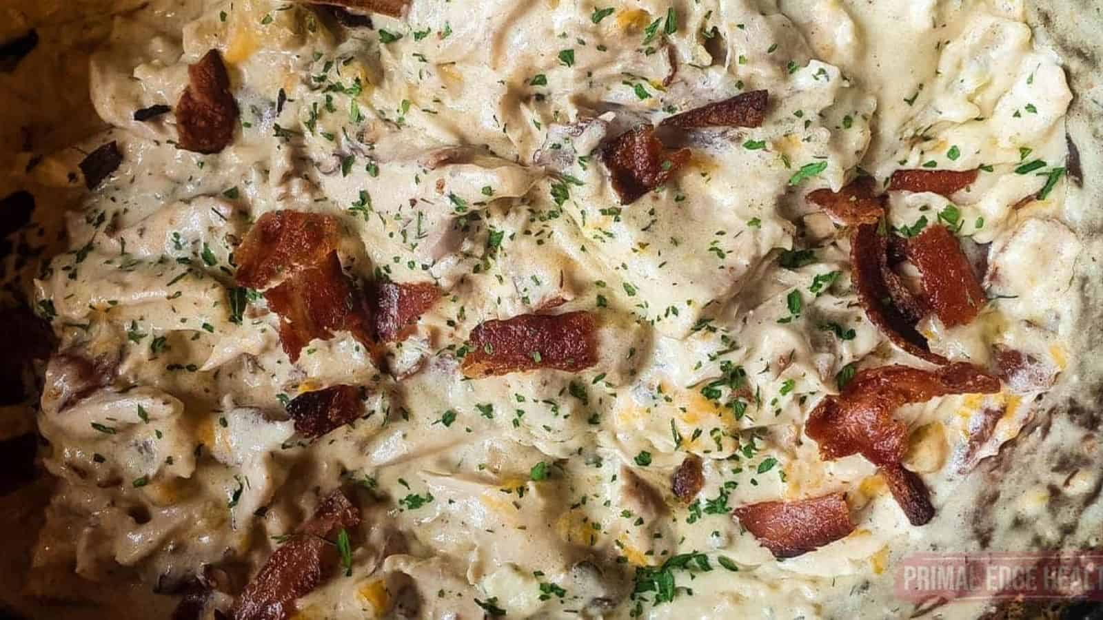 A picutre of cheesy chicken with bacon and dried parsley.