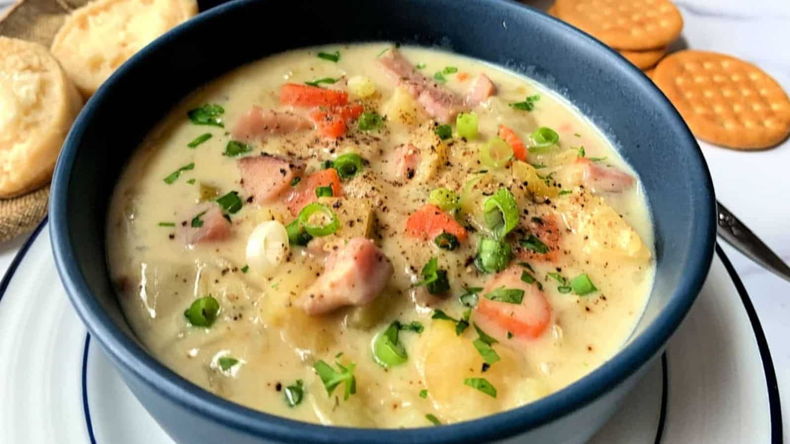 A blue bowl of ham and potato soup.