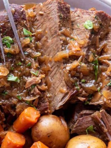 A plate of slow cooker London broil with a side of veggies.