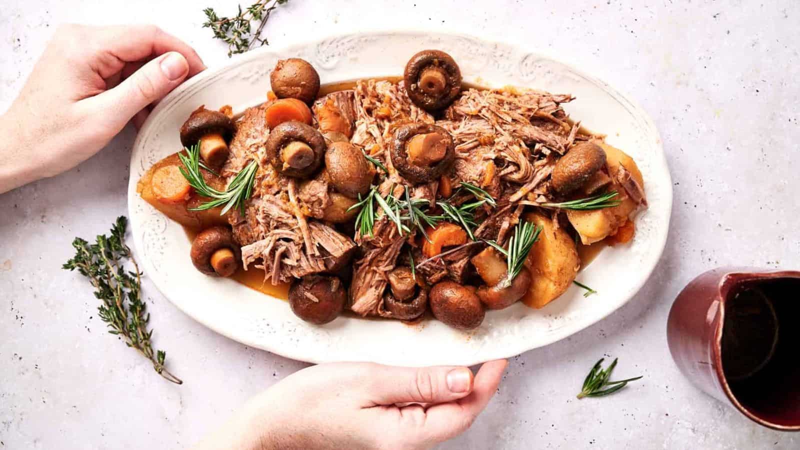 Someone holding a plate of slow cooker pot roast.