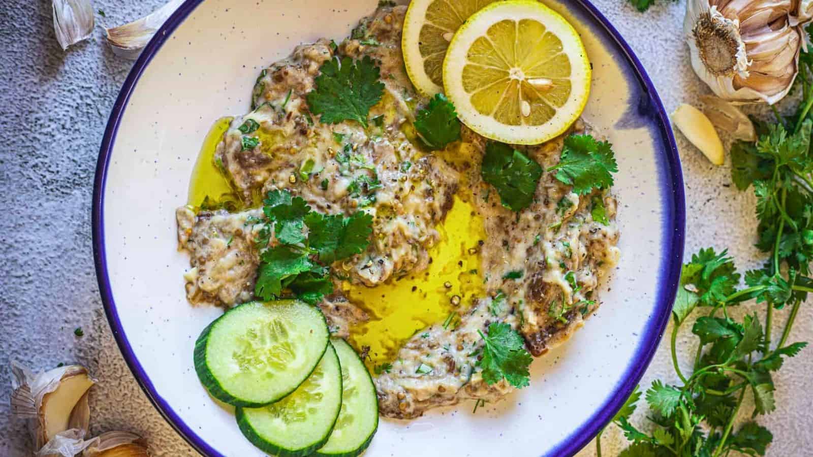 Baba ganoush on a plate with parsley and lemon.