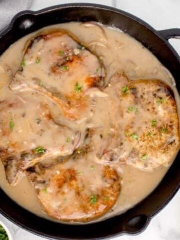 Top view of smothered pork chops in a pan.