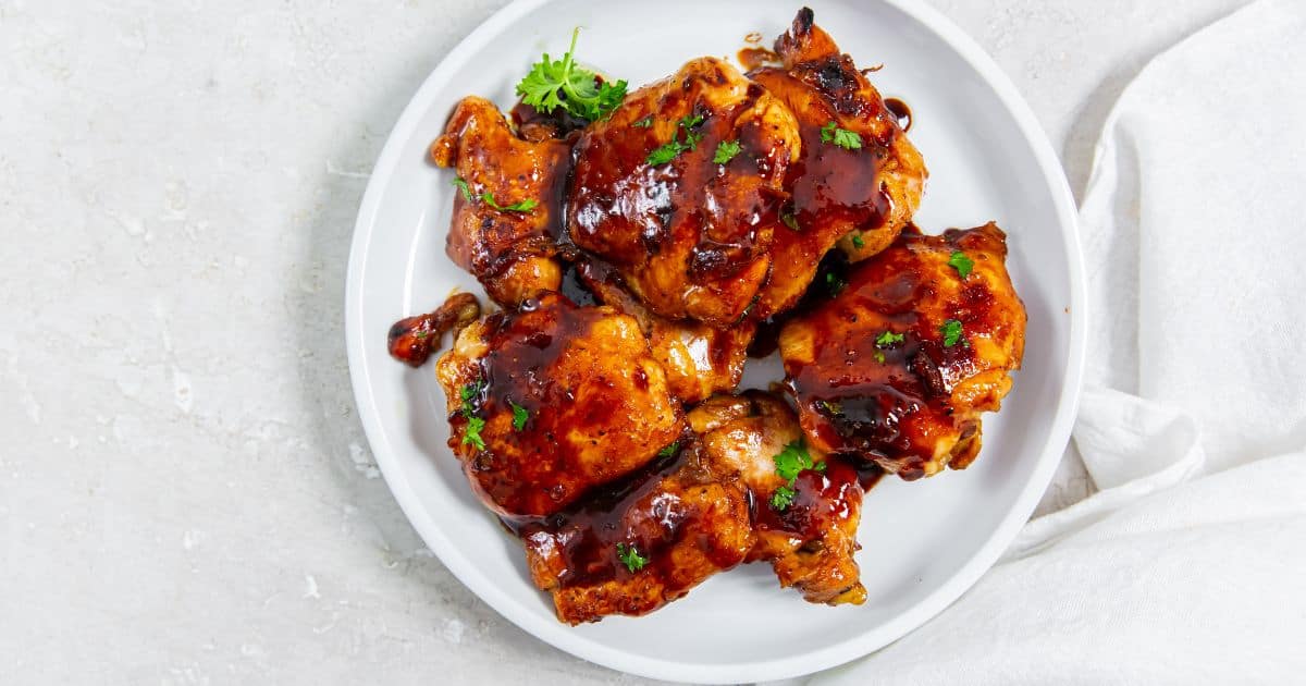 Honey Lemon Pepper Thighs with parsley on a white plate.