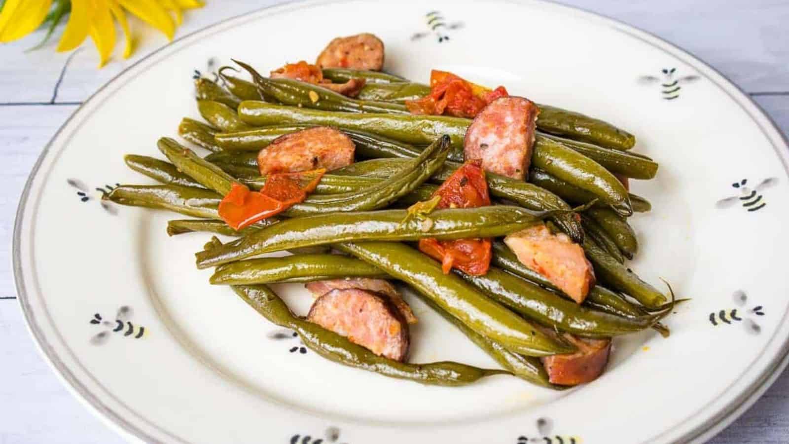 Green beans with sausage on a white plate.