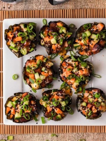 Eight spicy baked salmon sushi muffins on a square plate.