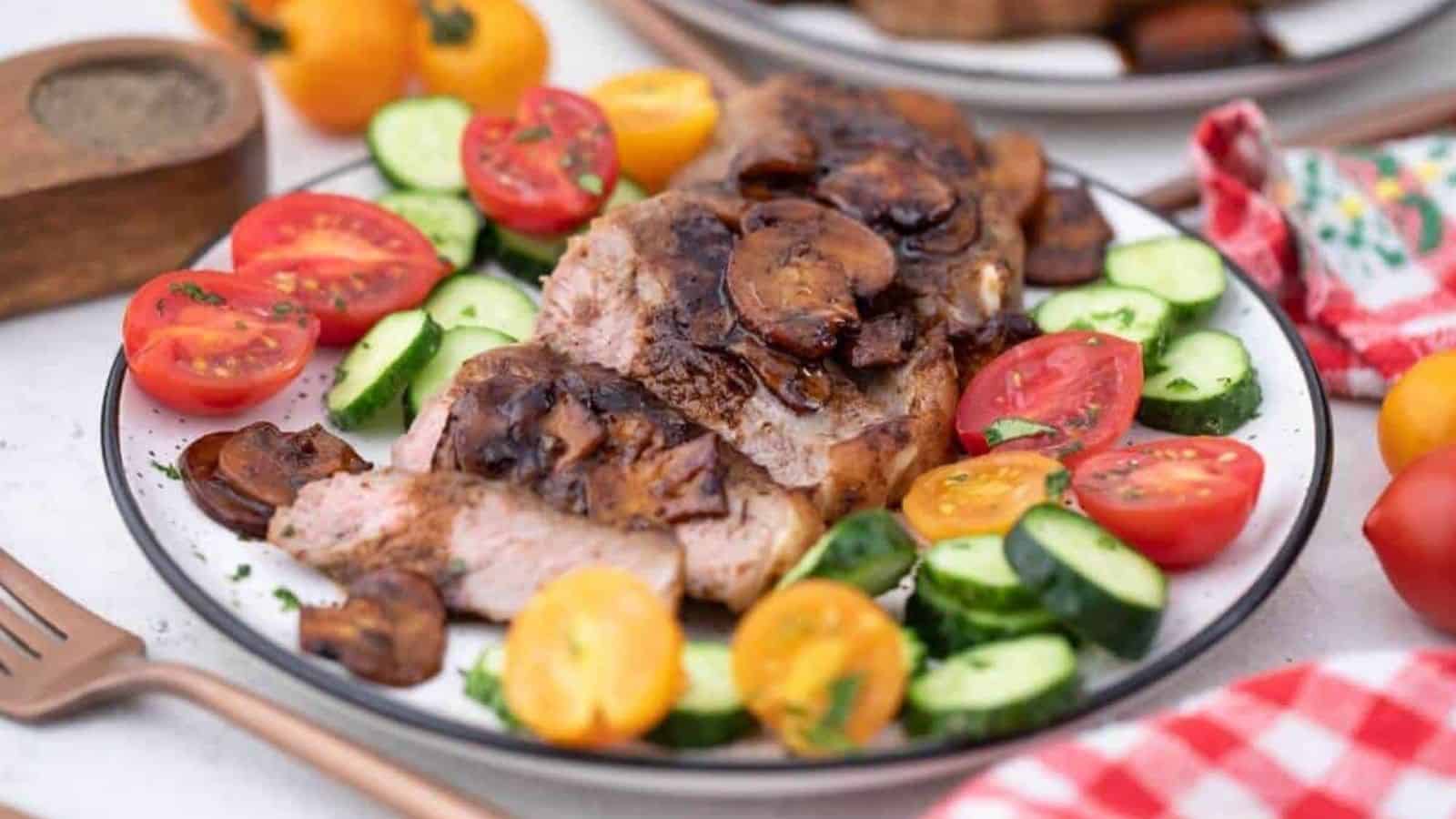 A plate with steak, tomatoes and cucumbers on it.