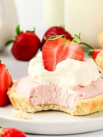 Bitten strawberry mousse tartlet in a plate.