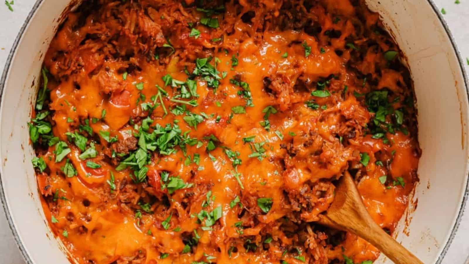 Stuffed bell pepper casserole in a pan with a wooden spoon.