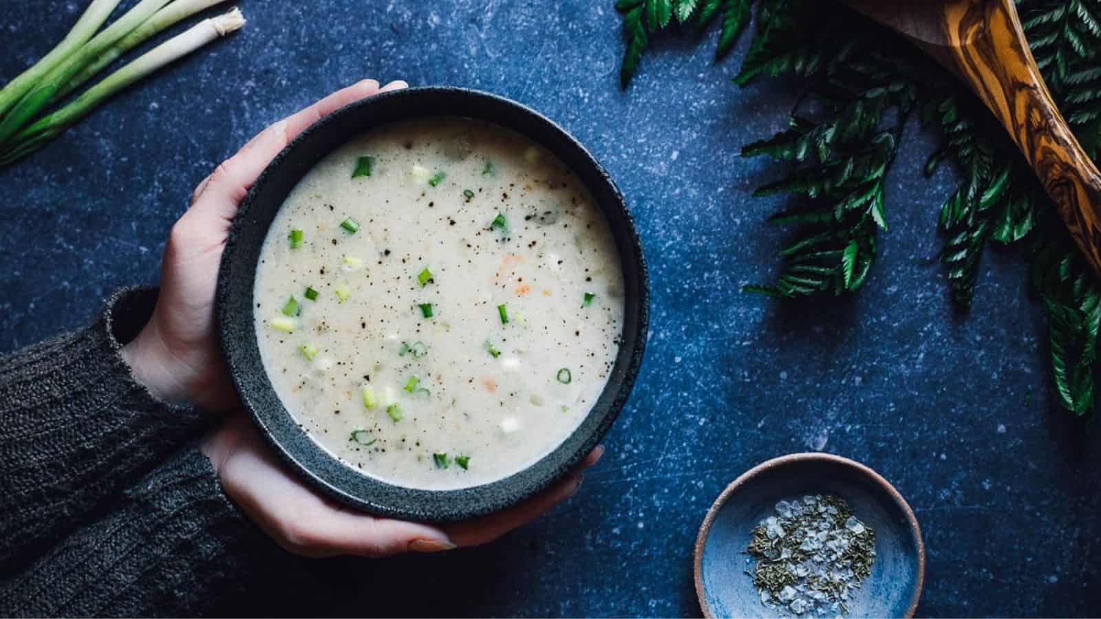 Someone holding a bowl of the best vegan potato soup.