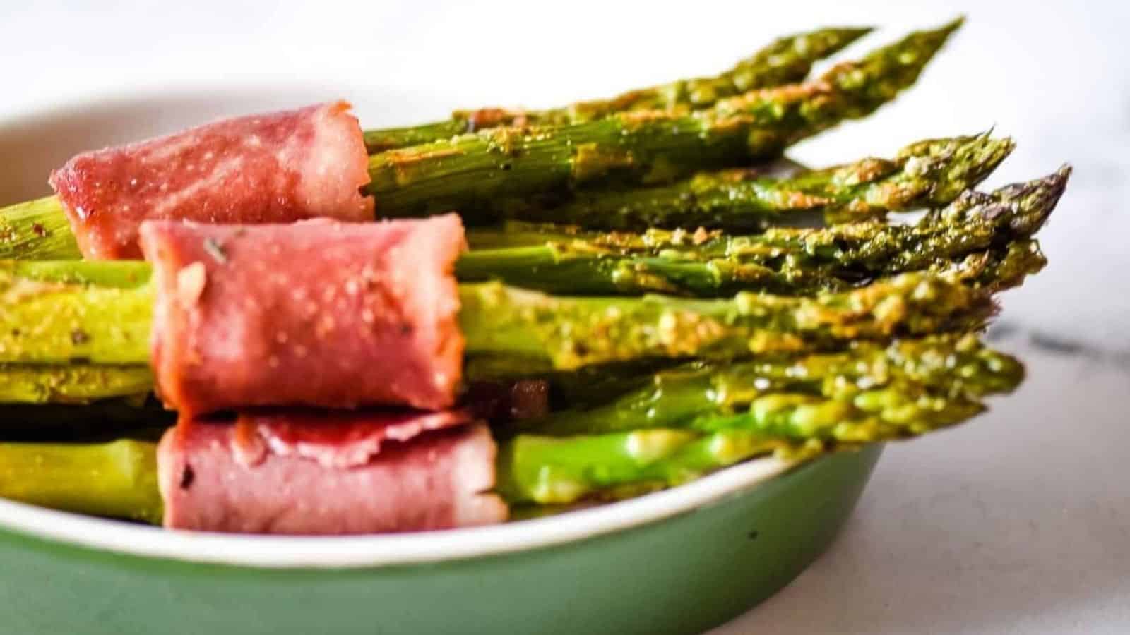 Closeup side view shot of turkey bacon wrapped asparagus bundles in a green dish.